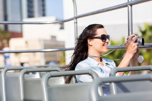 Reisende, die mit Digitalkamera von einem offenen Bus eine Stadt fotografiert